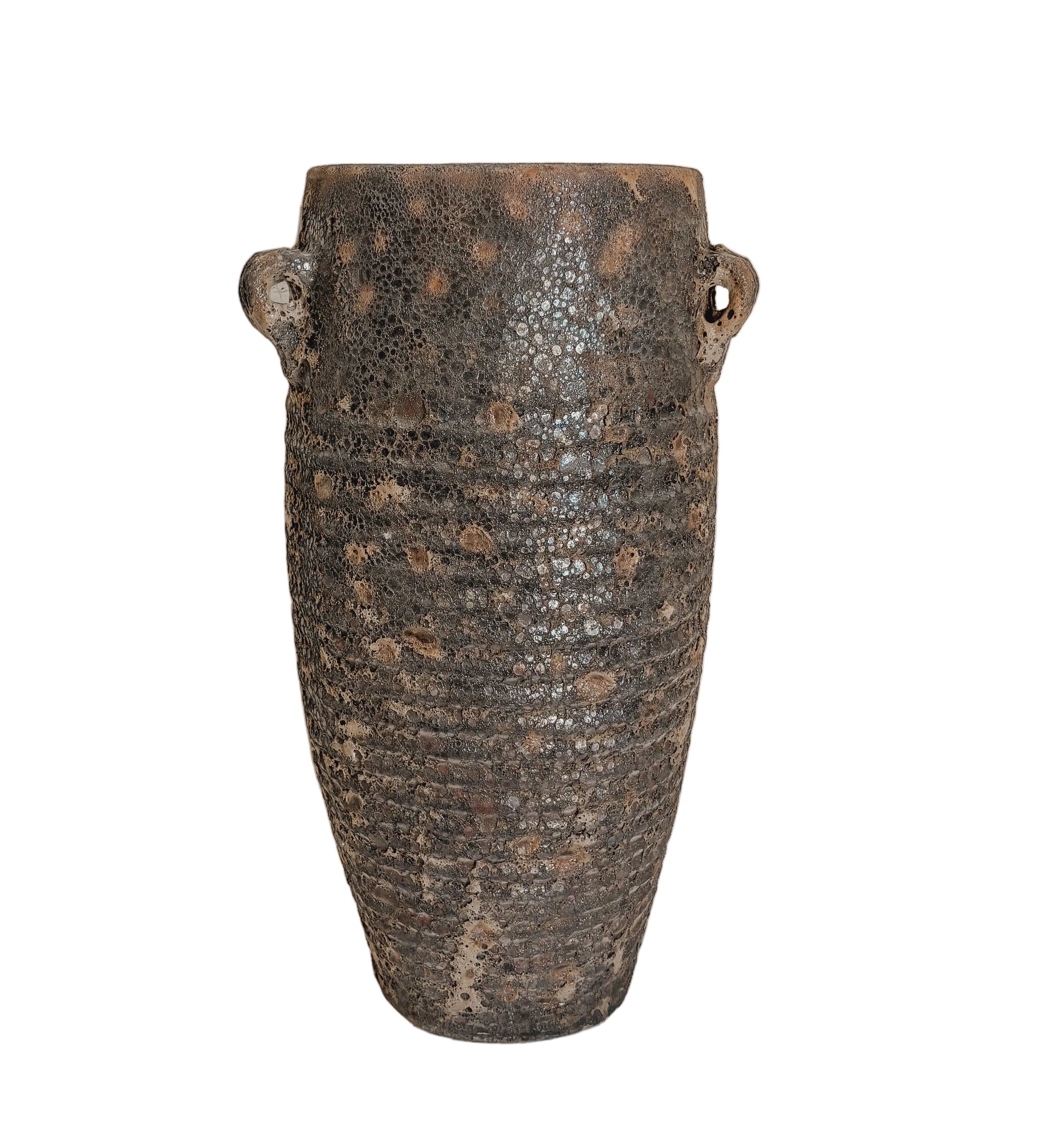 A rustic dark brown ceramic vase with a textured, speckled glaze and two small loop handles, displayed on a white pedestal against a neutral beige wall.